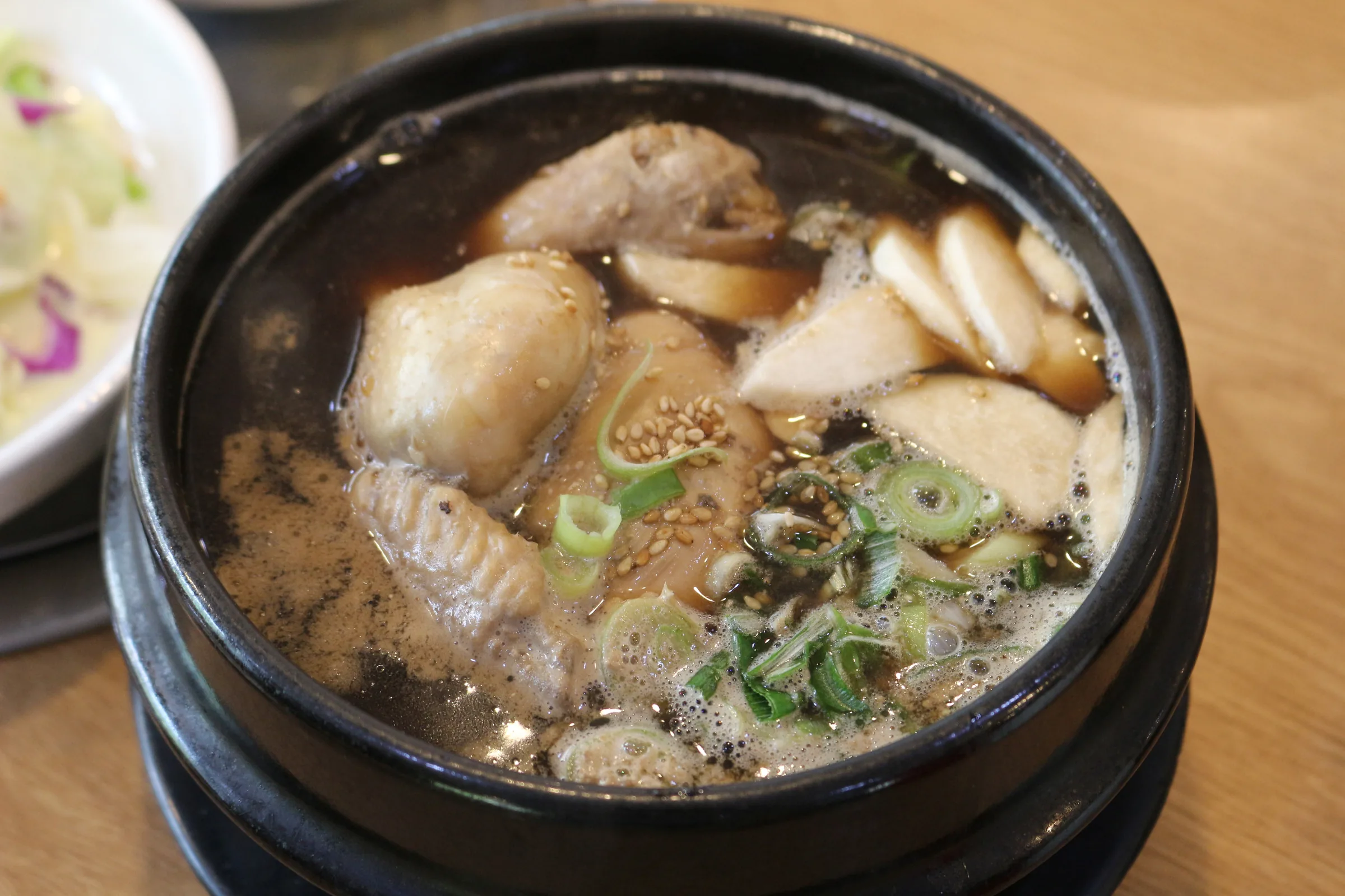 한방 육수에 담긴 닭고기와 송송 썬 파, 깨를 올린 뚝배기