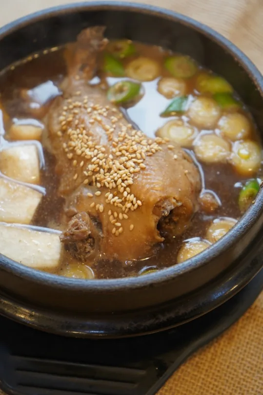 뚝배기 속 작은 닭 한 마리와 한방 육수, 깨와 파